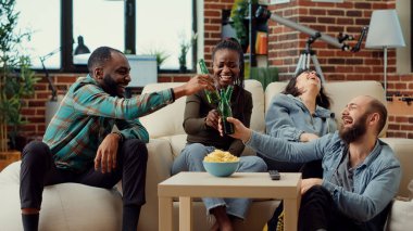 Neşeli arkadaşlar televizyonda komedi filmi izleyip gülüyor, bira şişelerini tokuşturuyor ve sosyal toplantılarda eğlenceli filmlerin tadını çıkarıyorlar. Eğlence programlarıyla eğleniyorum. Üçayak atışı.