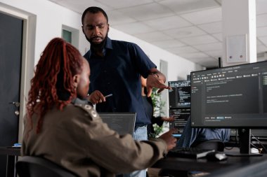 Bilgisayarda html kodunu öğrenen Afrika kökenli Amerikalı mühendisler büyük veri ofisindeki masa başında oturuyorlar. İçinde html betiği olan veritabanı sistemi üzerinde çalışan yazılım geliştiricileri