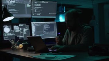Erkek programcı esniyor ve yeni arayüz üzerinde çalışıyor, gece geç saatlerde uykulu hissediyor. Yorgun yazılım mühendisi, güvenlik sistemi oluşturmak için veri tabanı bilgilerini yazmaktan yoruldu, yoruldu. El kamerasıyla..
