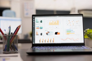 Boş bir modern ofisteki masada istatistiksel bilgili taşınabilir bilgisayar. Proje istatistikleri iş yerinde dizüstü bilgisayardaki finansal veri satış grafikleri, strateji analiz muhasebe kavramı.
