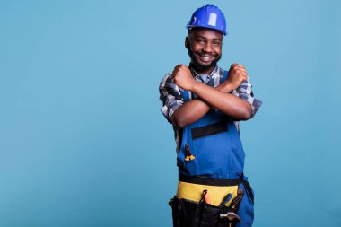 İnşaat işçisi, bir stüdyoda mavi bir arka planda durarak, silahlarla reddetme hareketi yapıyor. Reddetme ve yasaklamanın sembolünü katlanmış ellerle, tulum giyerek ve koruyucu bir şekilde gösteriyor.