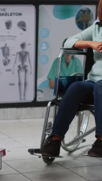 垂直ビデオ 車椅子のお客様は 処方薬やサプリメントを購入しようと 専門家の助けを受けています 社会福祉士と一緒に薬局に来る障害のある女性は 丸薬や — ストック動画