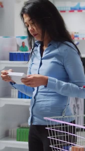 垂直录像 亚洲妇女检查药架上的药盒 希望购买处方药和药品保健产品 客户核对补充资料单张 — 图库视频影像