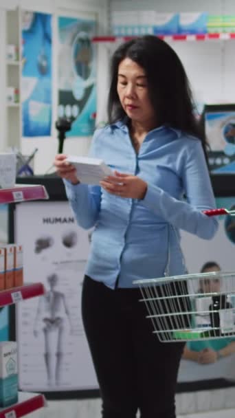 Вертикальне Відео Жінка Перевіряє Скриньки Вітамінів Полицях Аптеки Дивлячись Пакети — стокове відео