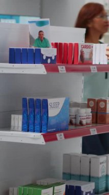 Dikey video: Eczanedeki ilaç kutularına bakan erkek müşteri, tıbbi tedavi ve vitamin arıyor. İlave almadan önce Asya 'daki yetişkinler ilaç paketlerini analiz ediyor.