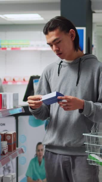 Vertikales Video Junger Mann Checkt Der Drogerie Kisten Mit Nahrungsergänzungsmitteln — Stockvideo