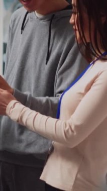 Dikey video: Genç müşteri akıllı telefondan uzmanlara reçete gösteriyor, ilaç ve sağlık tedavisi bulmaya çalışıyor. Çalışanlardan yardım alan bir adam eczane haplarına bakıyor.