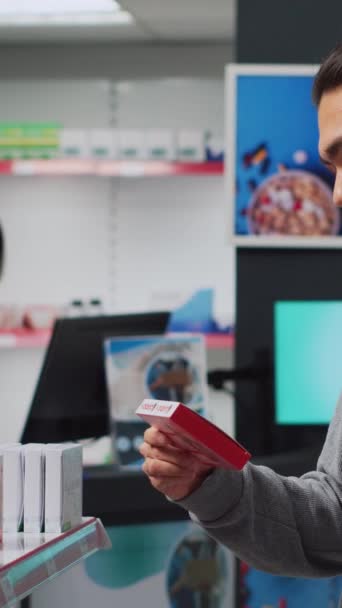 Вертикальне Відео Азіатський Чоловік Читає Листівку Коробці Таблетками Аптеці Перевіряє — стокове відео