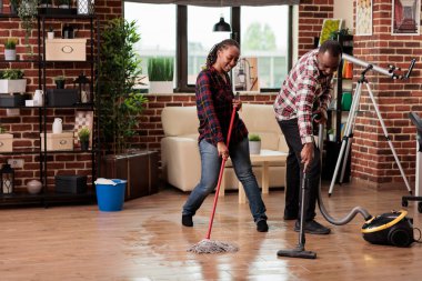 Afro-Amerikalı çift temizliği eğlenceli ve heyecan verici hale getiriyor. Ev bakımını pozitif enerji ve iyi titreşimlerle yapma zamanı. Koca kahkahalarla güldü karısının yüksek sesle şarkı söylemesini dinledi.