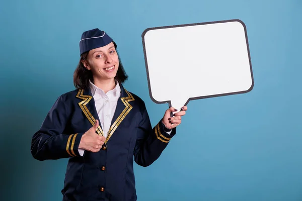 Uśmiechnięta Stewardesa Trzymająca Białą Pustą Bańkę Pokazująca Kciuk Górze Stewardesa — Zdjęcie stockowe