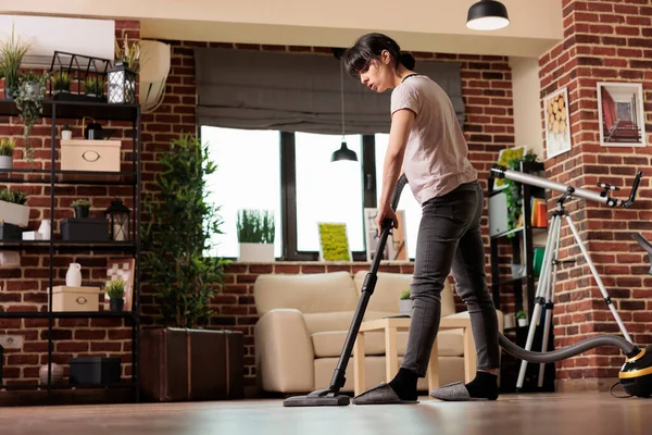 タイルの床に掃除機を使用して女性 春のクリーニングに集中 主婦は週に一度の掃除を自宅で行います すべてをきれいに保つことに専念します 低角度表示 — ストック写真