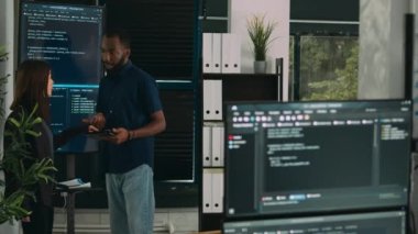 Yazılım programcıları büyük ekrandaki ve tabletteki algoritmalardan bahsediyorlar, html betik dilini analiz ediyorlar. Sistem mühendislerinden oluşan bir ekip terminal penceresi ve sunucu arayüzünde veritabanını tartışıyor.