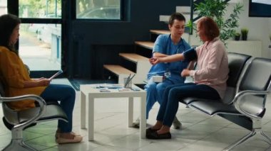 Uzman, sağlık merkezindeki bekleme odasında kan ve nabız basıncını ölçen tonometrede hipertansiyonu kontrol ediyor. Asyalı hasta kardiyoloji testiyle check-up yapıyor..
