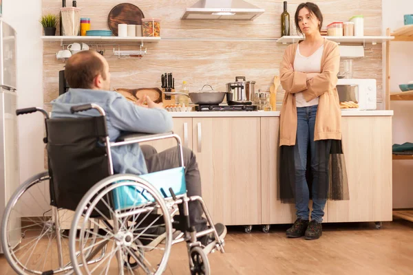 由于与坐轮椅的残疾丈夫不和 妻子在厨房里烦躁不安 事故后有行走残疾的瘫痪残疾人融入社会 — 图库照片