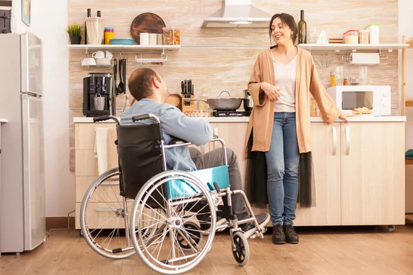 残疾男子在做饭时坐在椅子上与妻子交谈 事故后有行走残疾的瘫痪残疾人融入社会 — 图库照片