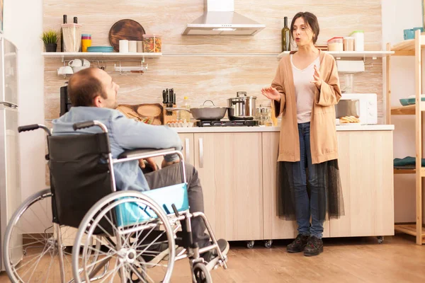 轮椅上的残疾人和妻子在厨房里有冲突 事故后有行走残疾的瘫痪残疾人融入社会 — 图库照片