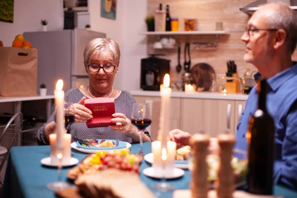 Rentnerin Mit Geschenkbox Vom Ehemann Während Des Abendessens Zum Beziehungsjubiläum — Stockfoto