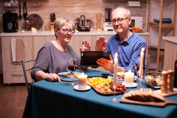 Lächelndes Senioren Paar Winkt Während Videotelefonie Und Abendessen Der Küche — Stockfoto