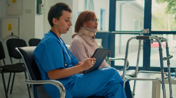 Krankenschwester Berät Patientin Mit Halsbandspange Und Gehgestell Und Notiert Unfallverletzungen — Stockfoto