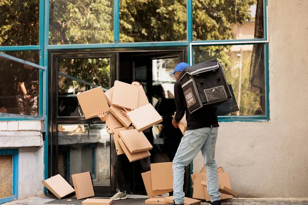 Reckless courier dropping pizza boxes pile at client, clumsy courier carrying office food order outdoors. Bad delivery service, careless clumsy man with falling fastfood packages stack