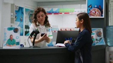 Eczane tezgahında ilaçların parasını ödeyen Asyalı bir müşteri. NFC ödemesini reçeteli ilaç ve kardiyoloji hapı almak için kullanıyor. İlaveler ve vitaminler satın alınıyor.