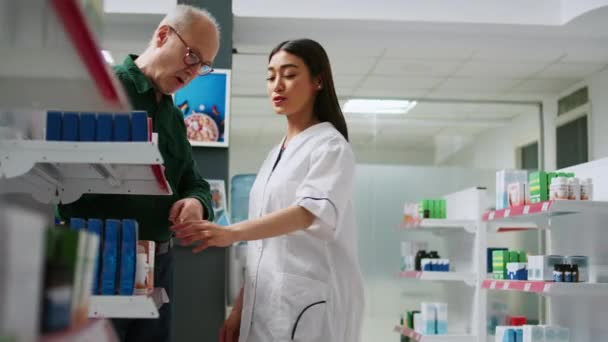 亚洲药剂师向老年人解释心脏科药物 在药店谈论医疗保健药物 帮助病人接受治疗 药物治疗和医疗救助的妇女 — 图库视频影像
