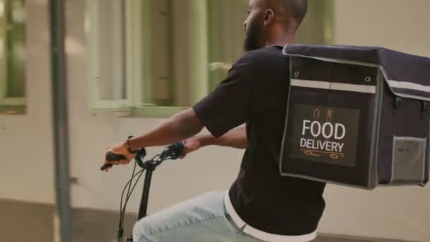 送货员乘自行车前往办公大楼入口 由年轻人担任送货员 非洲裔美国人快餐店员工 在街上骑着热袋自行车 — 图库视频影像