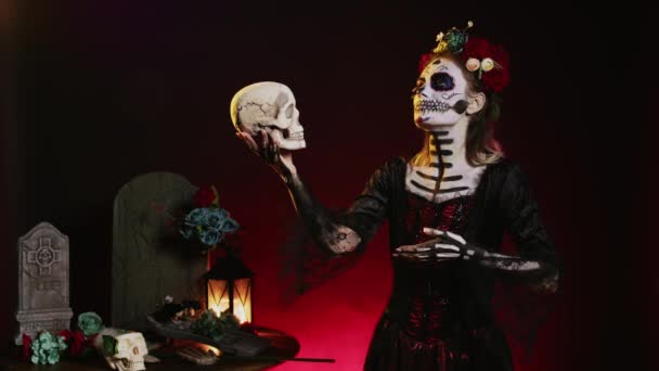 死のグラマラスな女性は黒い背景の上に頭蓋骨を見て 花の花輪とサンタのマウスの衣装を着ています ディオス ムエルトスの聖なるメキシコの組織のように振舞う 祭りを構成する — ストック動画