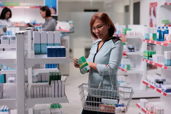 女性客户检查货架上的维生素盒 希望购买医疗补充剂和药品 在药房检查医疗用品及药物的包装 — 图库照片
