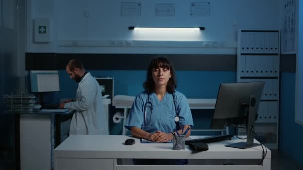 Lächelnde Arzthelferin Die Schreibtischtisch Steht Und Krankheitssymptome Computer Überprüft Arzthelferin — Stockvideo