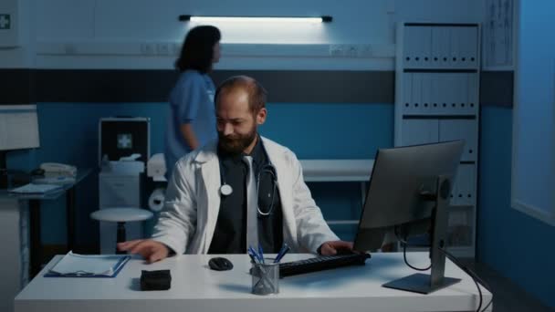 Wyczerpany Lekarz Ogólny Pracujący Godzinami Biurze Szpitalnym Wpisujący Wiedzę Temat — Wideo stockowe