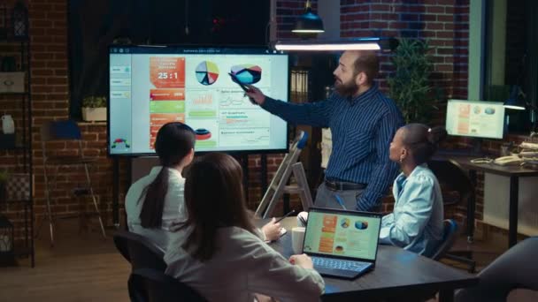ビジネスミーティング 企業分析レポートプレゼンテーション 戦略計画 統計図付きのデジタルボードを指している男は 同僚のチームは 役員室でブレインストーミングズーム — ストック動画