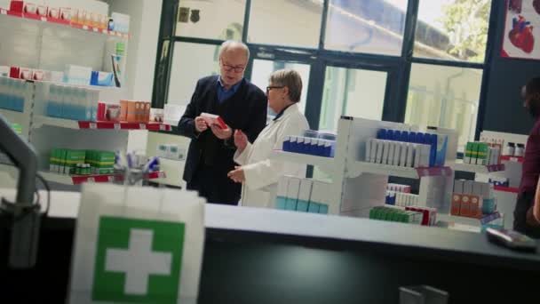 Apotekare Förklarar Hjärtmedicin Piller Recept Till Senior Klient Läsa Broschyr — Stockvideo