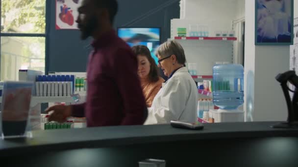 Aptekarz Rozmawia Klientem Suplementach Tabletkach Patrząc Pudełka Lekami Półkach Apteki — Wideo stockowe