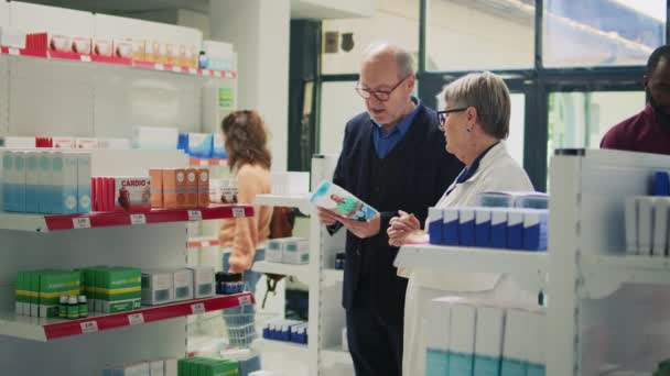 Idősebb Férfi Aki Egészségügyi Ellátásról Kérdez Gyógyszereket Olvas Gyógyszerész Doboz — Stock videók