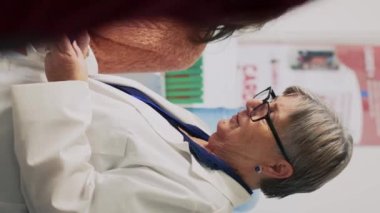 Dikey video: Eczacıyı dinleyen, hastalık tedavisi hakkında tavsiye veren, ilaç ve takviyeler hakkında sorular soran kadın hasta. Genç yetişkin ilaç almak için vitamin kutusu broşürlerini kontrol ediyor..