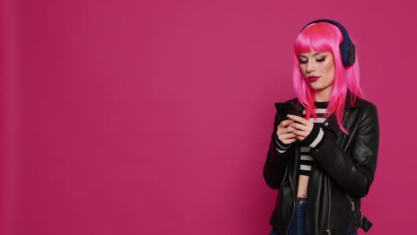 분홍색 메시지를 보내고 헤드폰으로 음악을 쾌활하고 자신감 스마트폰에서 미디어 온라인 — 비디오