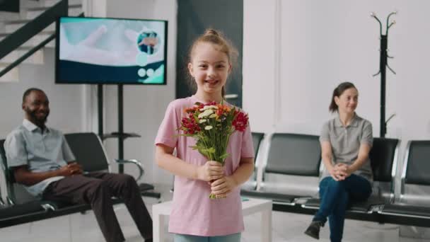 Усміхнена Маленька Дівчинка Тримає Букет Квітів Лікарняній Зоні Очікування Готуючись — стокове відео