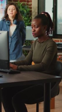 Dikey video: Ofis çalışanlarından oluşan bir ekip, profesyonel bilgisayar yazılımı kullanarak yaratıcı ajans stüdyosunda 3 boyutlu içerik yaratmak için beyin fırtınası yapıyor. Dijital proje geliştirme üzerinde çalışan genç bayan çalışanlar