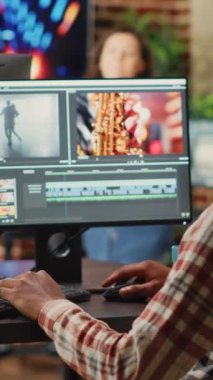 Dikey video: Afrika kökenli Amerikalı çalışan multimedya yazılımları üzerine video düzenleme, odak ışıklandırma ve renk derecelendirme kullanılarak. Erkek film yapımcısı pc multi monitörlerinde film montajı üzerinde çalışıyor.