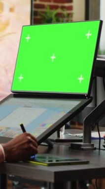 Dikey video: Bilgisayarda yeşil ekran arkaplan kullanan genç içerik yaratıcısı, düzenleme yazılımı ile fotoğrafları rötuşluyor. İzole edilmiş krom anahtar görüntüleme ve boş telif alanı ile çalışan erkek çalışan.