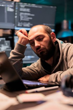 Ofis masasında uyuyakalan yorgun bilişim bilmecesi arayüz programlama üzerinde çalışıyor, gece geç saatlerde başını eliyle tutuyor. Veritabanı sistemini kodladıktan sonra uyuyan çok çalışan geliştirici yoruldu.