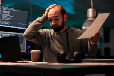 Geç saatlere kadar çalışan yorgun yazılım geliştiricisi teslim tarihine yetişmesi için baskı altında hissediyor. Kaynak kodu programlamak için html betiği ve terminal penceresi kullanılması, aşırı çalışma ve vurgulama.