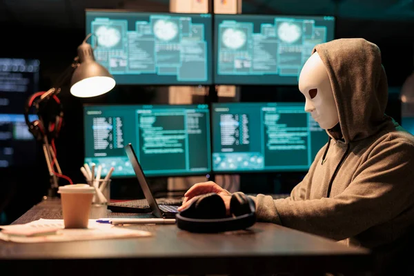 带着蒙面身份黑客服务器的网络恐怖分子 行事神秘 并试图闯入计算机系统 带着面具和头罩的黑客窃取在线数据库信息 — 图库照片