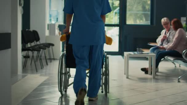 간호사가 휠체어를 환자를 지원하고 보건소 로비에서 검진을 있습니다 장애와 장애가 — 비디오