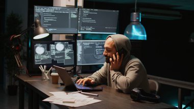 Bilgi işlem geliştirme ofisinde telefonla konuşan genç bir programcı uzaktan konuşma için akıllı telefonu kullanıyor. Html kodu üzerinde çalışan erkek mühendis geliştiriyor, cep telefonu tutuyor. El kamerasıyla..