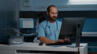 Hastane ofisinde sağlık tedavisini planlarken saatlerce hasta hastalıkları uzmanlığında çalışan pratisyen hemşire. Arka plandaki doktor sabit telefona cevap veriyor. Tıp konsepti