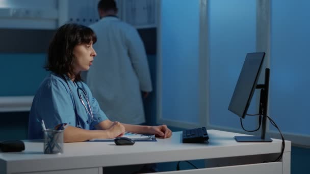 Assistente Médico Verificando Relatório Doença Computador Enquanto Trabalhava Tratamento Paciente — Vídeo de Stock