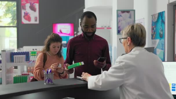 Fiatal Vásárlók Vitaminokat Gyógyszereket Vásárolnak Gyógyszertár Pénztárában Okosórát Mobiltelefont Használnak — Stock videók
