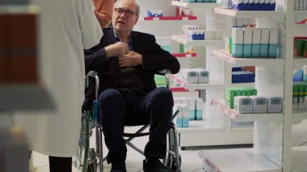 Ανώτερος Άνδρας Αναπηρική Καρέκλα Και Κοινωνικός Επιστάτης Μιλάει Τον Φαρμακοποιό — Αρχείο Βίντεο